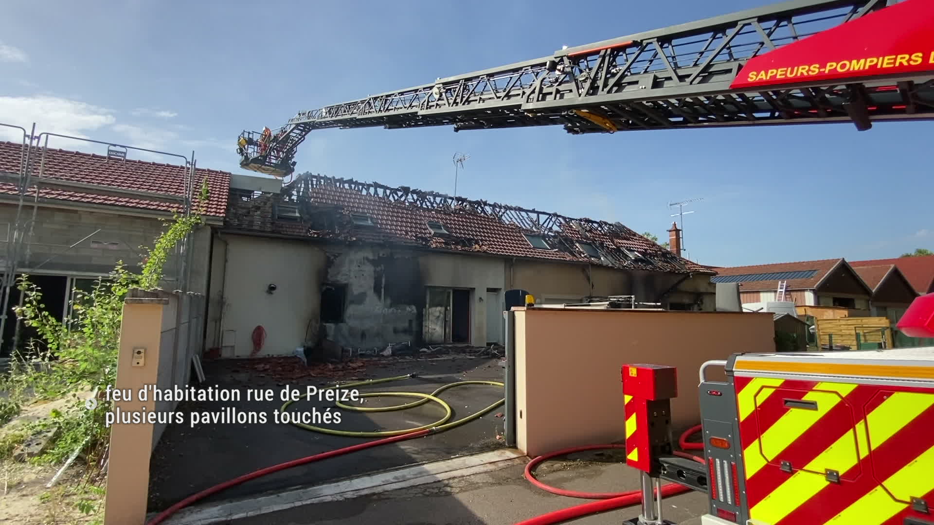 Pompiers intervenant sur un incendie de pavillon, toiture endommagée, échelle de secours déployée