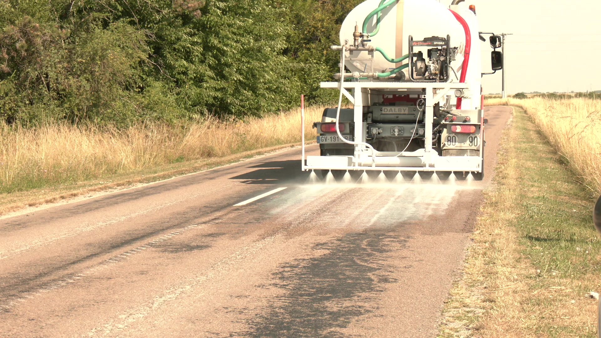 Tracteur John Deere vert aux grandes roues jaunes circulant sur une route de l'Aube par temps ensoleillé