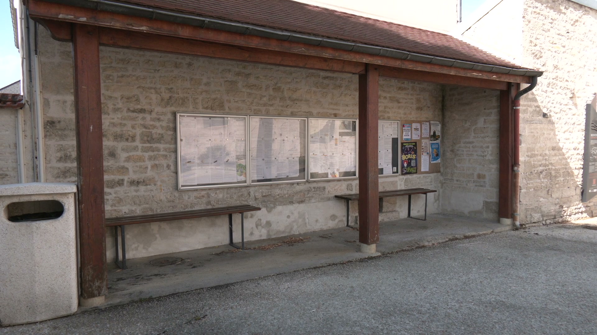 Abri de bus en pierre avec deux bancs et panneaux d'affichage municipaux, village rural de l'Aube