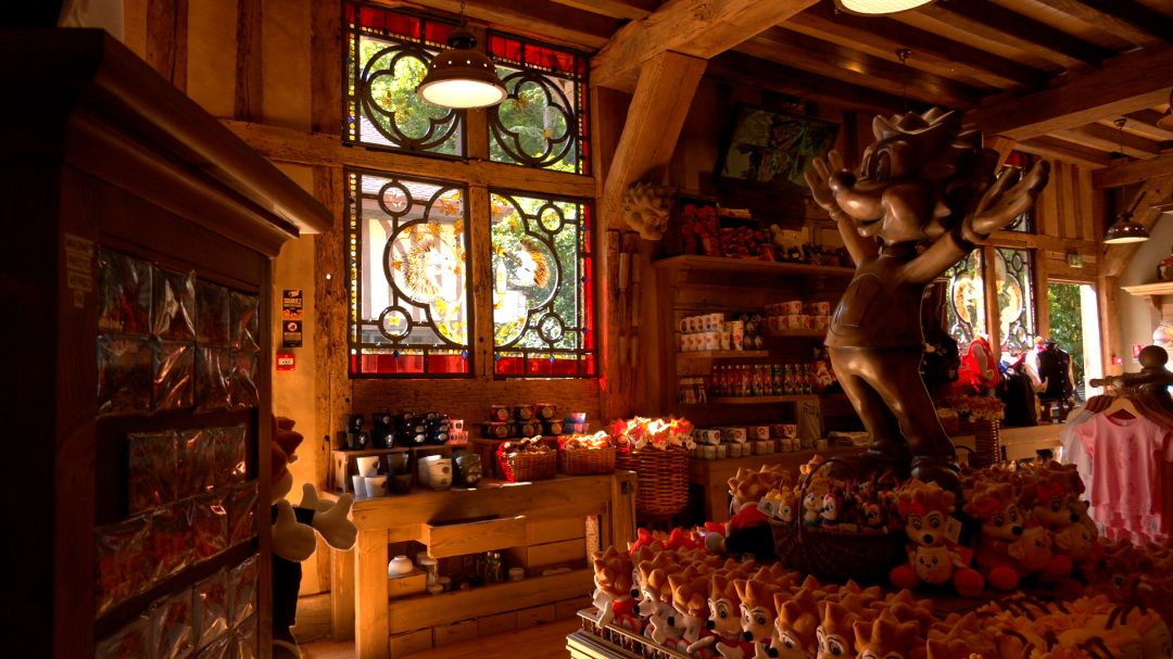 Boutique de Nigloland avec vitraux à motifs rouges et statue de la mascotte hérisson