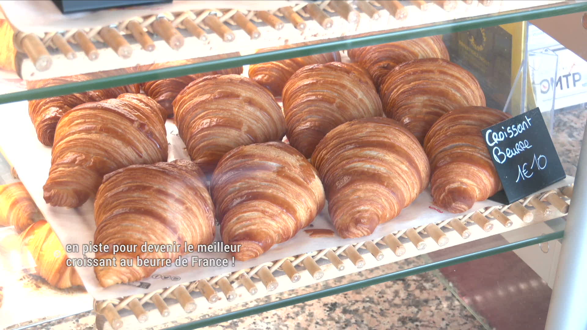 Croissants au beurre dorés exposés en vitrine de boulangerie, étiquette ardoise à 1,10 euro