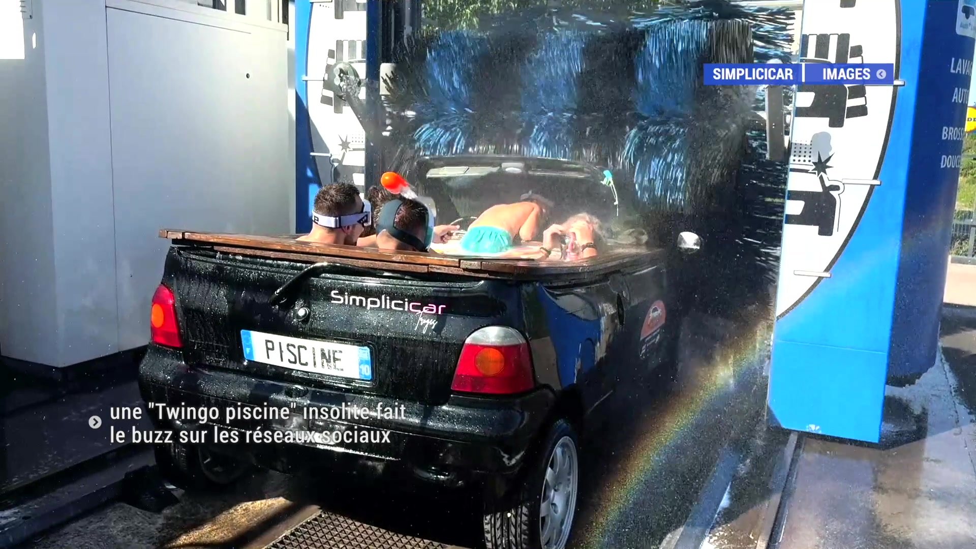 Groupe de jeunes en short de bain poussant la Twingo noire immatriculée PISCINE vers les rouleaux du lavage automatique