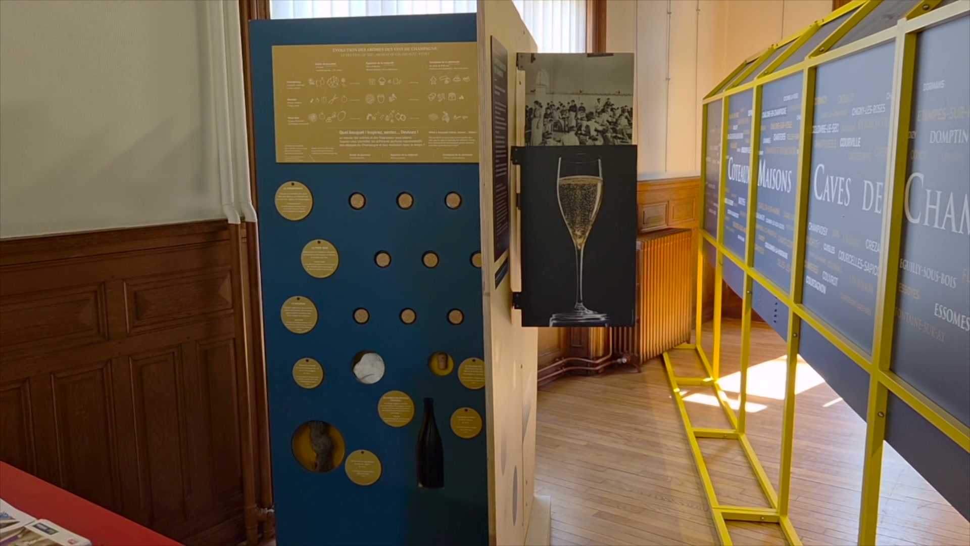 Panneaux d'exposition sur le vignoble champenois avec une flûte de champagne et des modules interactifs à disques dorés