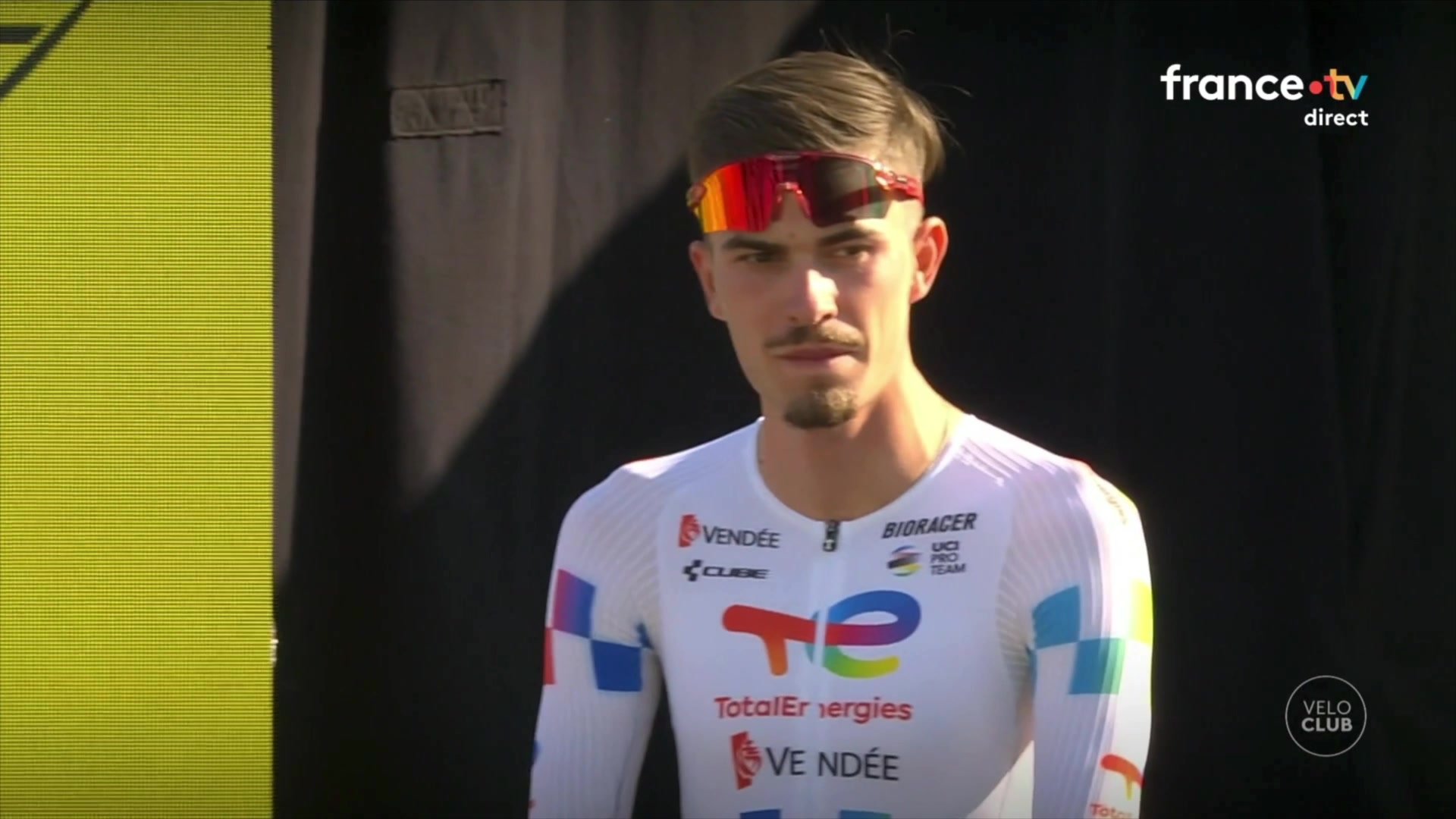 Joris Delbove dans un magasin de vélos, mannequin en maillot TotalEnergies derrière lui