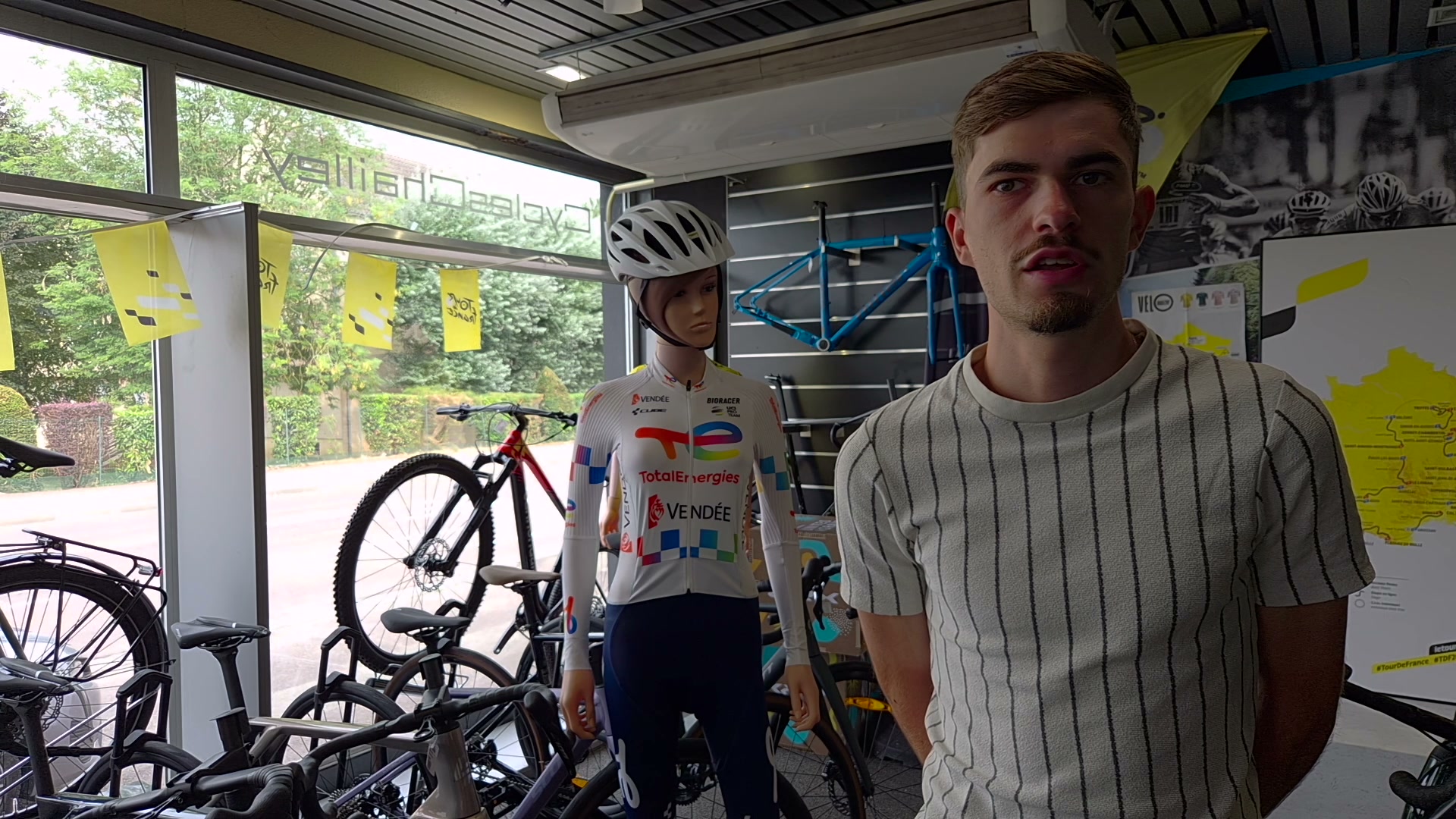 Joris Delbove interviewé dans un magasin de vélos avec un mannequin en maillot TotalEnergies