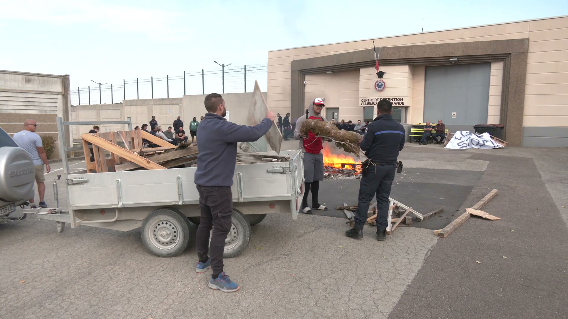Agents pénitentiaires entretenant un feu devant le centre de détention de Villenauxe-la-Grande, remorque chargée de