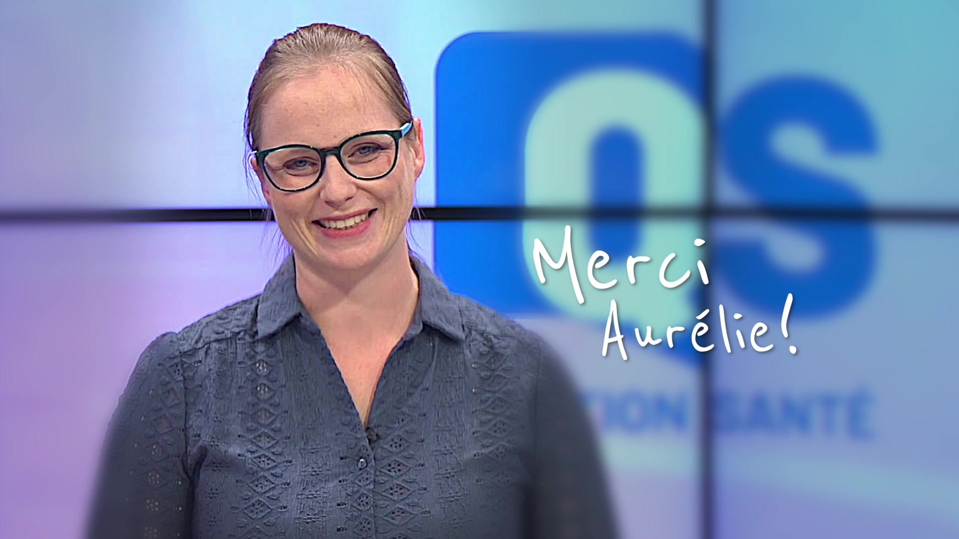 Aurélie Juignet souriante sur le plateau du JT de Canal 32, micro-cravate visible, fond bleu avec lettres JT
