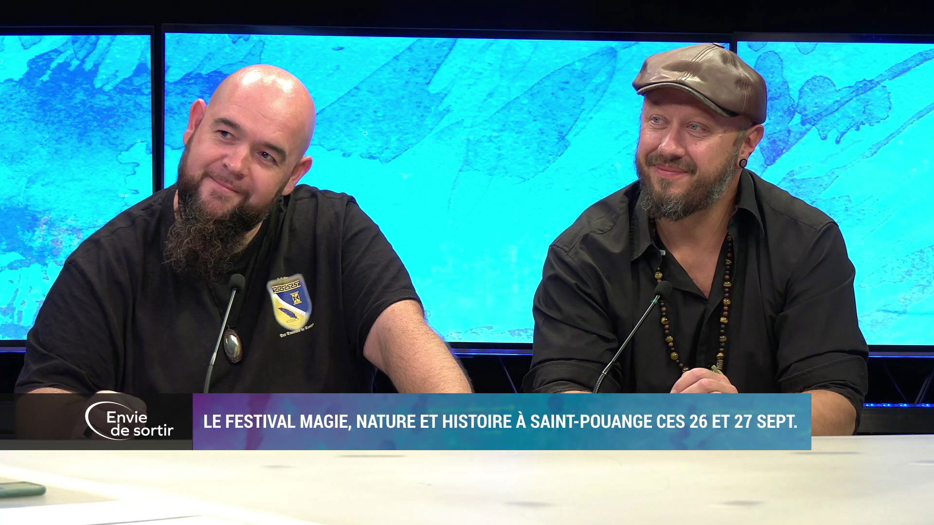 Deux hommes en tenue noire souriants sur le plateau d'Envie de sortir, fond bleu turquoise