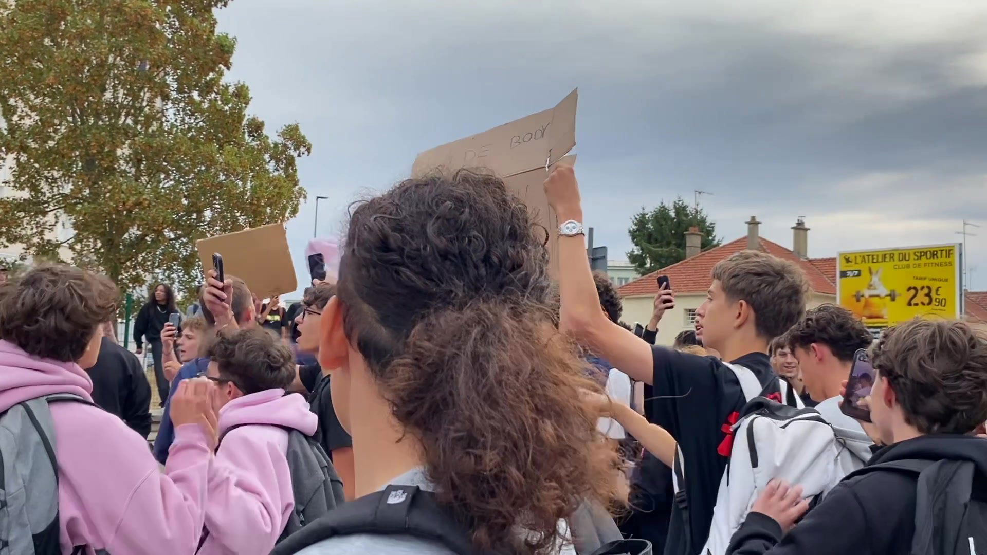 Lycéen prenant la parole devant une foule d'élèves rassemblés à l'extérieur du lycée
