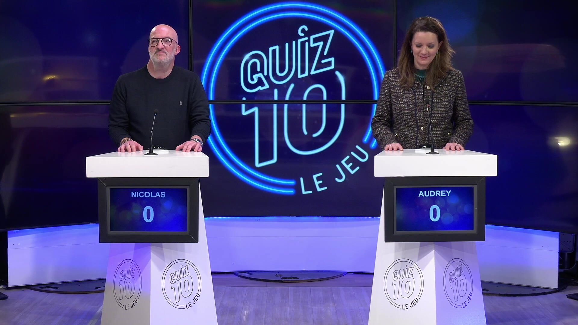 Plateau de Quiz 10 avec deux candidats face aux pupitres de jeu et le logo lumineux de l'émission