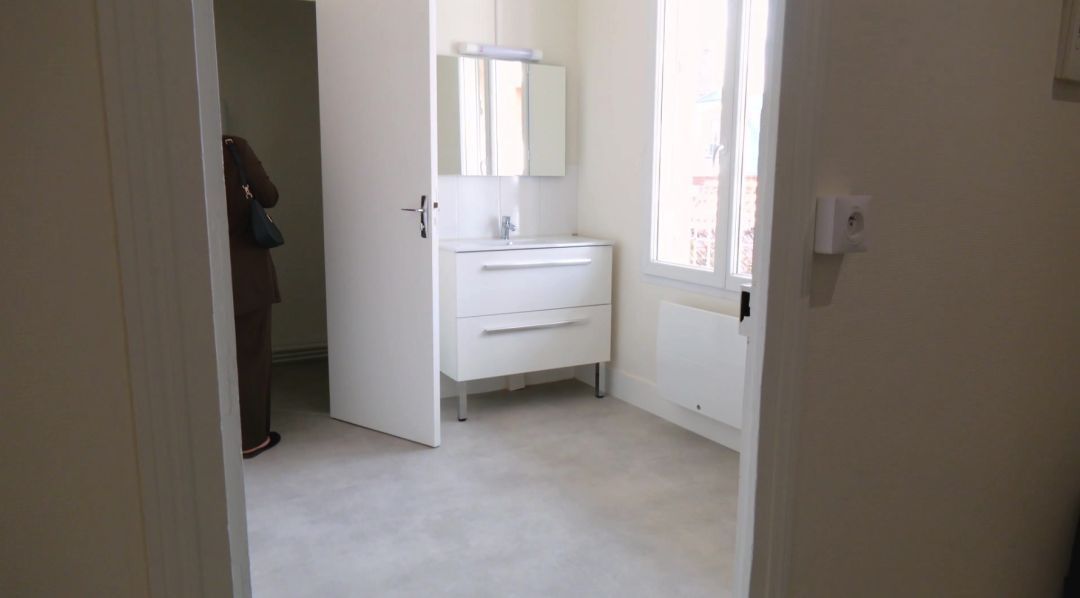 Salle de bain rénovée avec meuble vasque blanc et miroir