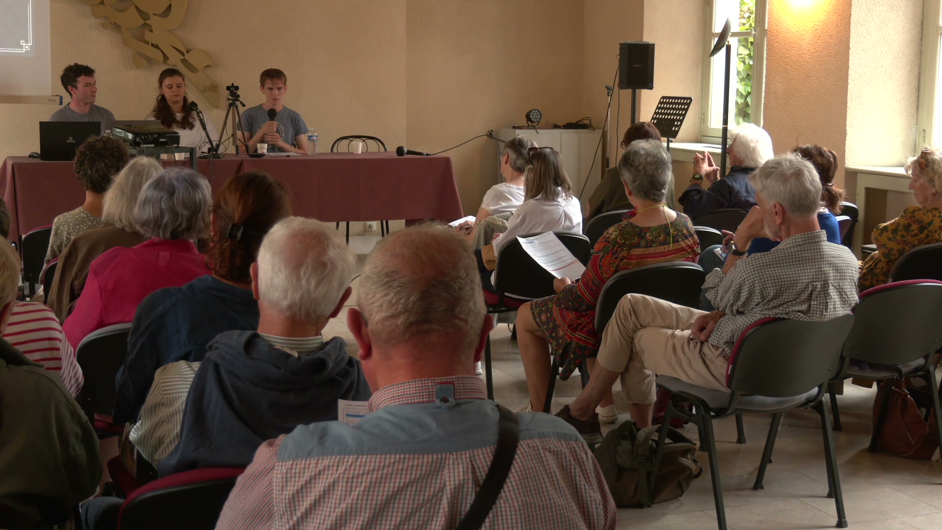 Salle de réunion avec public assis face à une table de présentation