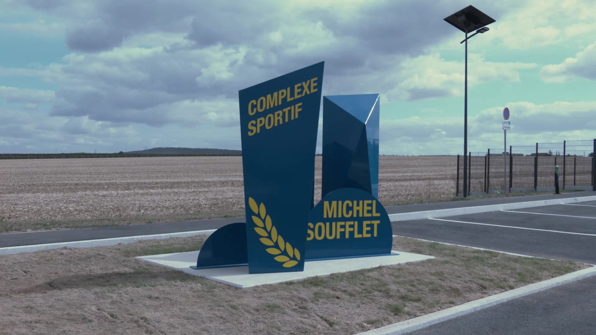 Trois personnes discutent sur une piste d'athlétisme bleue avec des tours de refroidissement en arrière-plan