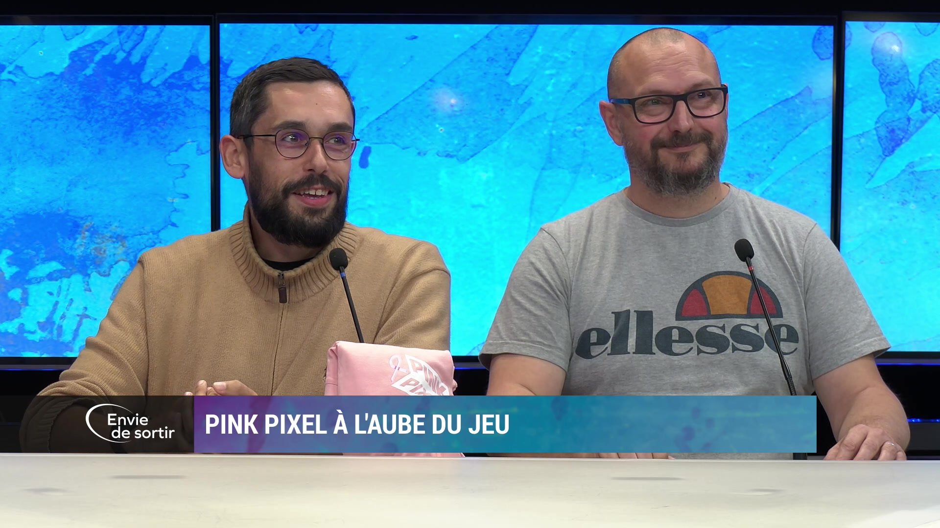Deux hommes souriants sur le plateau d'Envie de sortir, bandeau Pink Pixel à l'aube du jeu