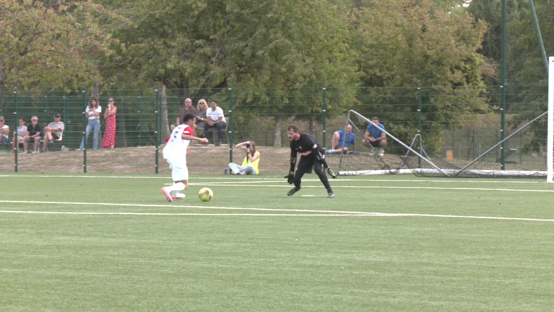 Fabien Azil en veste blanche Uhlsport devant un terrain de football synthétique