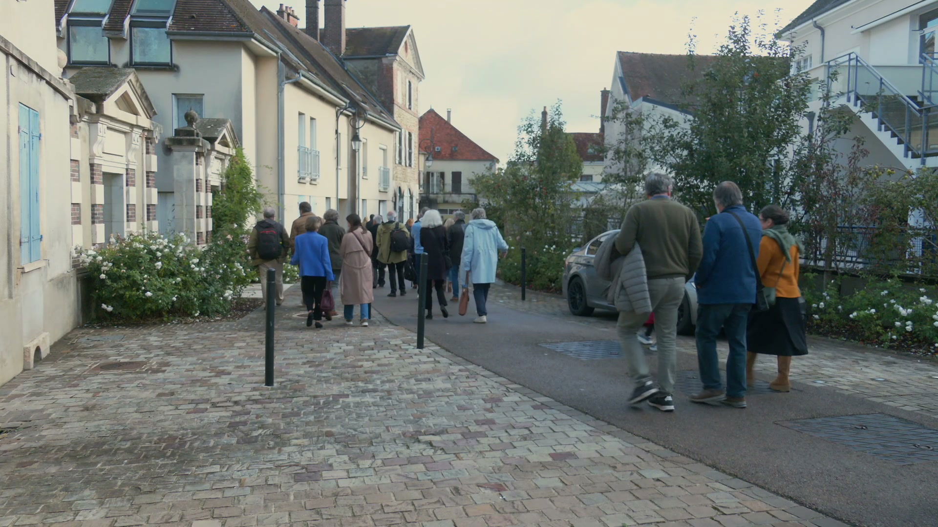 Groupe de visiteurs marchant sur une rue pavée longeant des façades anciennes à Ervy-le-Châtel