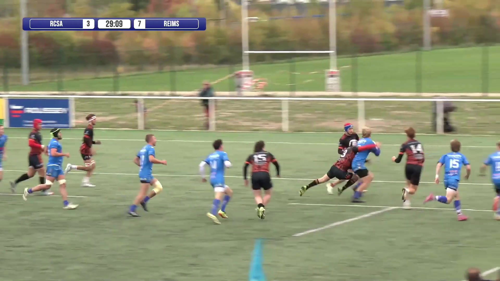 Joueurs du RCSA en maillot noir et rouge face à Reims en bleu sur la pelouse d'Echenilly, score 3-7 affiché