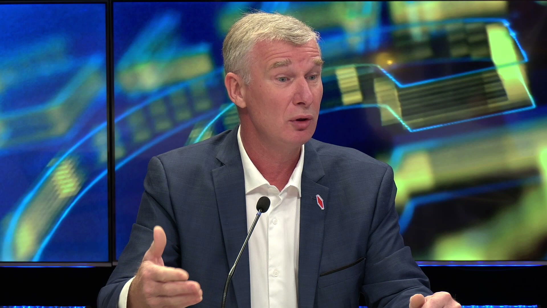 Pascal Brie en veste bleue, badge rouge au revers, s'exprime face à un micro sur le plateau de Canal 32