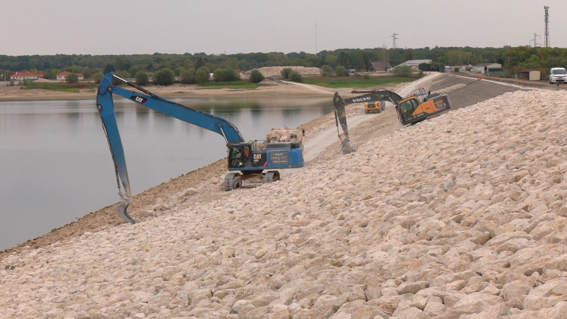 Passerelle métallique jaune surplombant le lac d'Orient, enrochements calcaires au premier plan