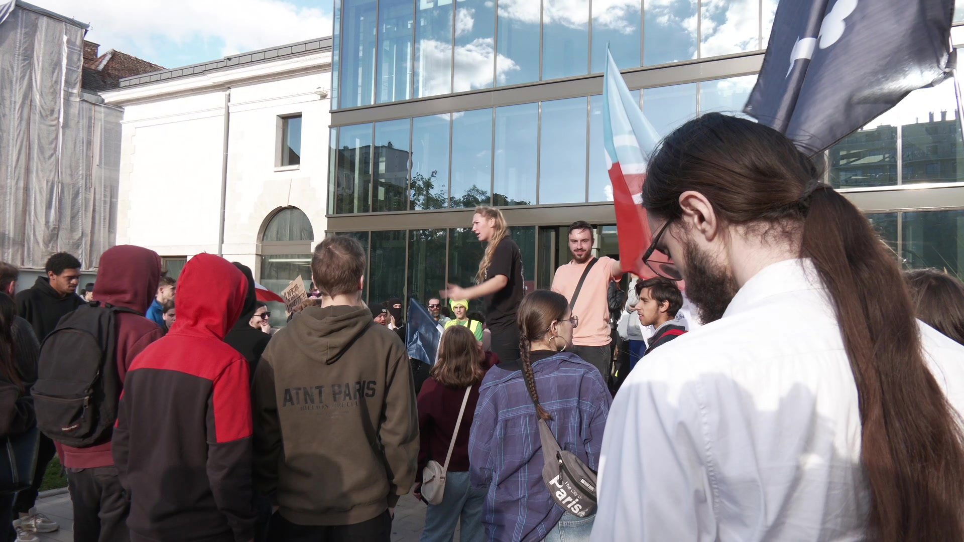 Plusieurs centaines de manifestants rassemblés sur une place urbaine à Troyes, drapeau rouge et noir brandi