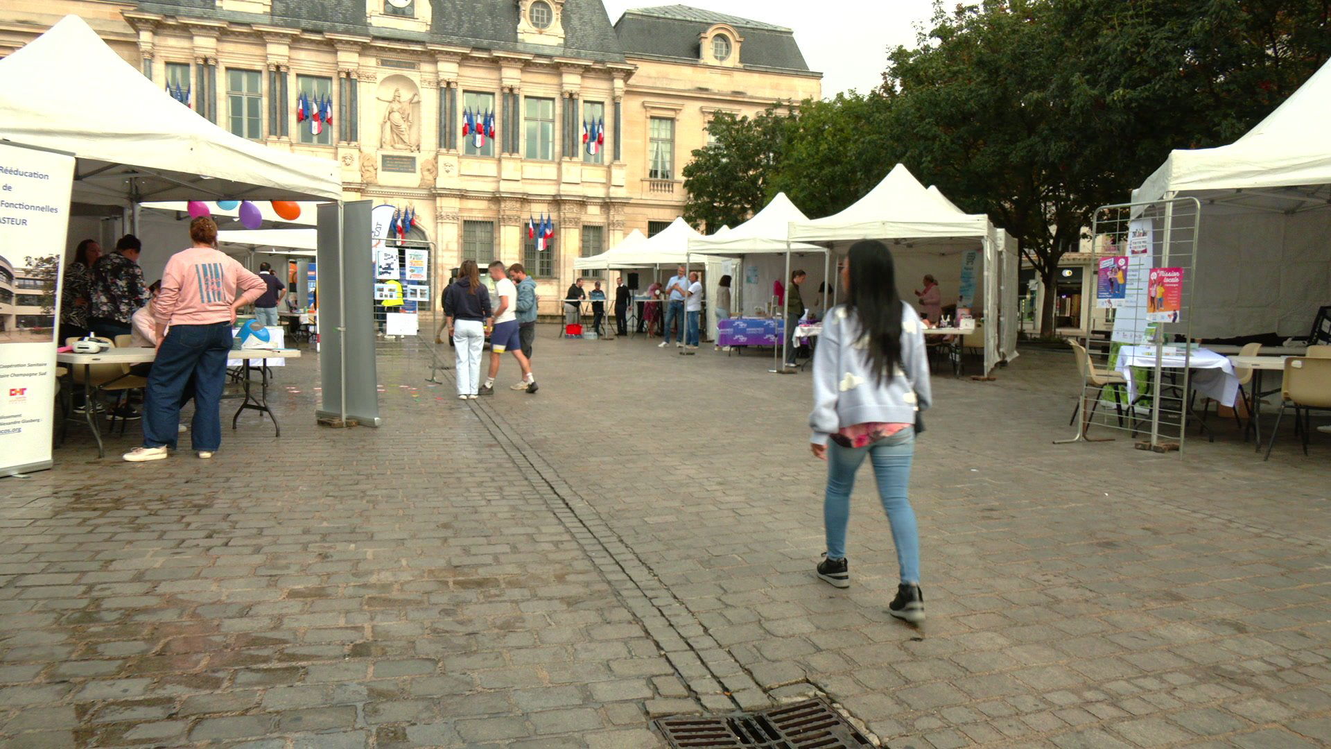 Stand de la Mission Locale de Troyes sous une tente blanche, avec participants assis autour d'une table et fauteuil roul