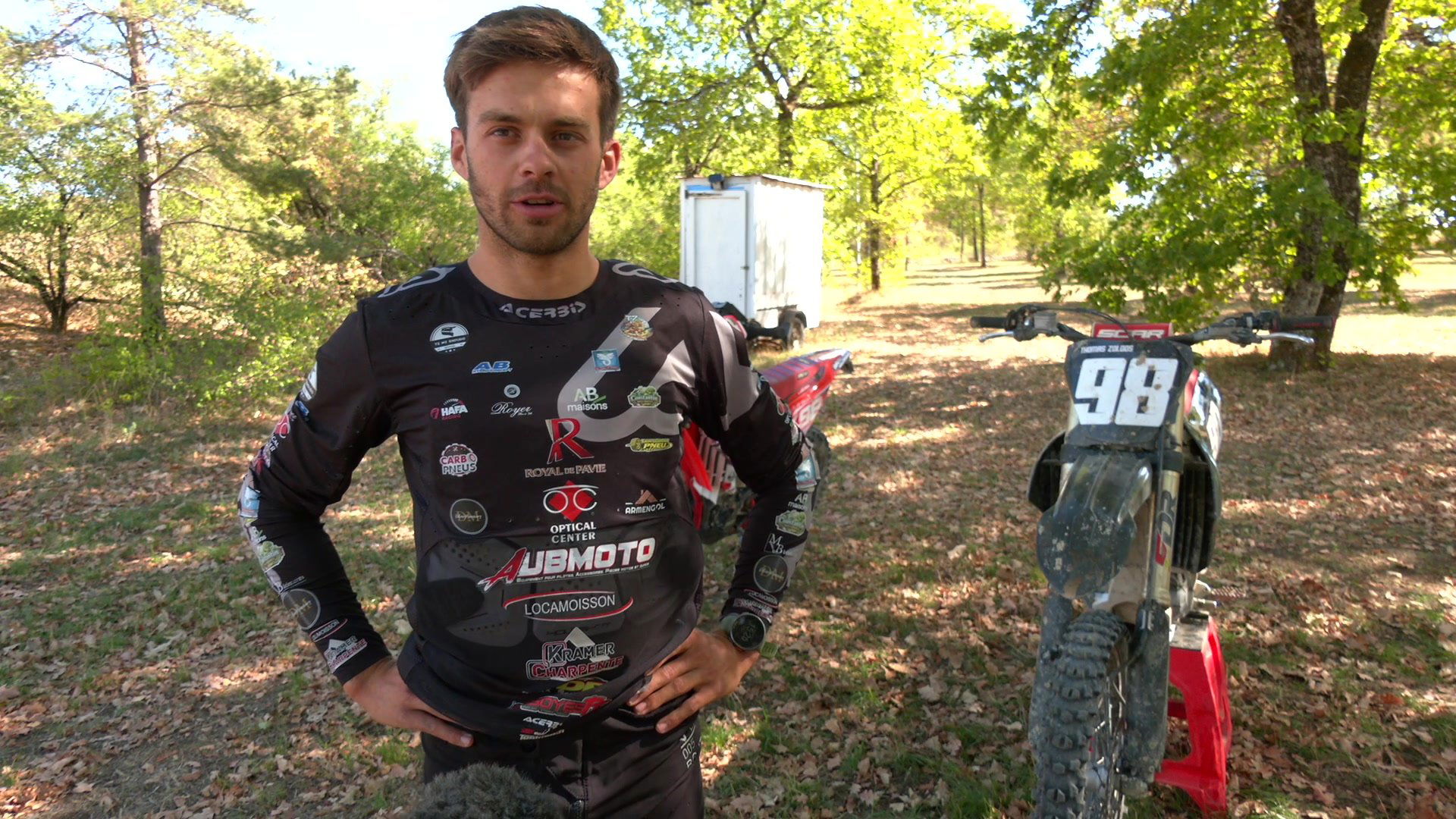 Thomas Zoldos en tenue de compétition devant sa moto numéro 98 dans un sous-bois