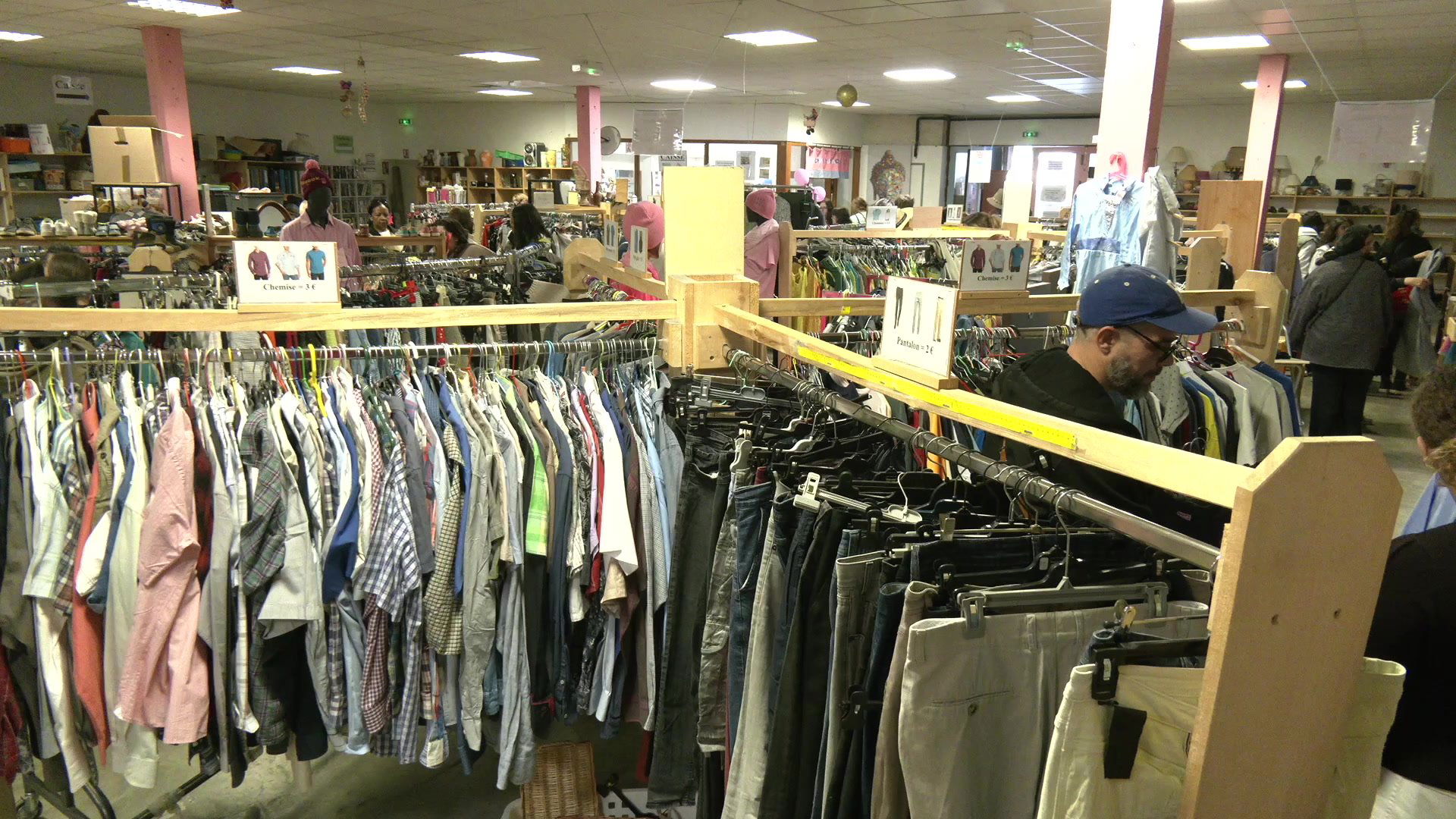 Vêtements et foulards colorés entassés sur un portant dans le magasin du Soutien Actif à Troyes